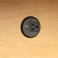 Built-in round desk power outlet with USB-A and USB-C charging ports and AC socket mounted in a wooden desk