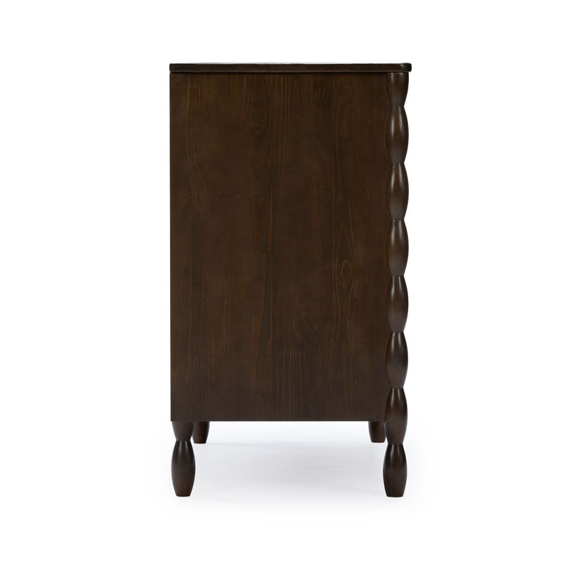 Dark brown wooden dresser side view with turned legs and scalloped side molding, classic bedroom chest of drawers
