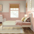 Pastel pink girl's bedroom with tufted headboard, yellow gingham bedding, mustard Roman shade, scalloped wainscoting and jute rug