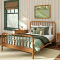 Cozy farmhouse-style child's bedroom interior with spindle wood bed, green quilted bedding, striped wallpaper, green-trim window, wooden nightstand, plush teddy bear and framed tennis artwork