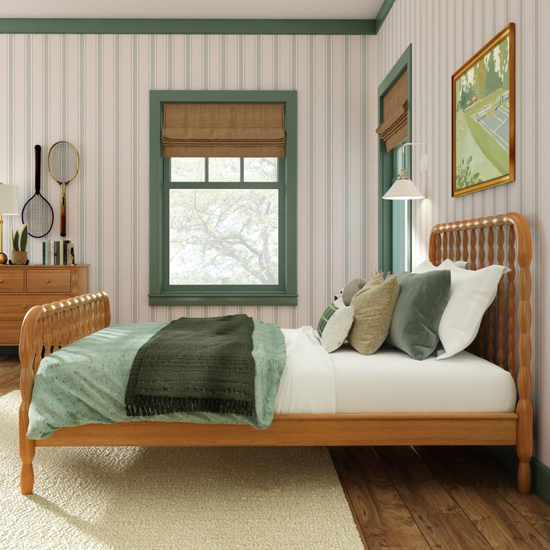 Cozy bedroom with wooden bed, green bedding, striped wallpaper, window with brown Roman shade, dresser and tennis rackets