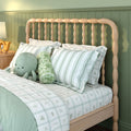 Cozy kids bedroom with light wooden spindle headboard green striped bedding and plush octopus toy