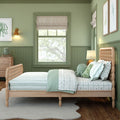 Cozy coastal kids' bedroom with green walls, wooden spindle bed, mint bedding, plush octopus toy, framed sea creature art, and woven wall lamp