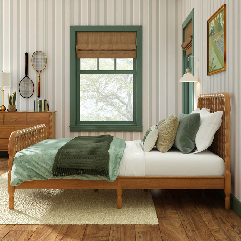 Cozy bedroom interior with green-trimmed window and brown Roman shade, wooden bed with green bedding, striped wallpaper, dresser and wall-mounted tennis rackets