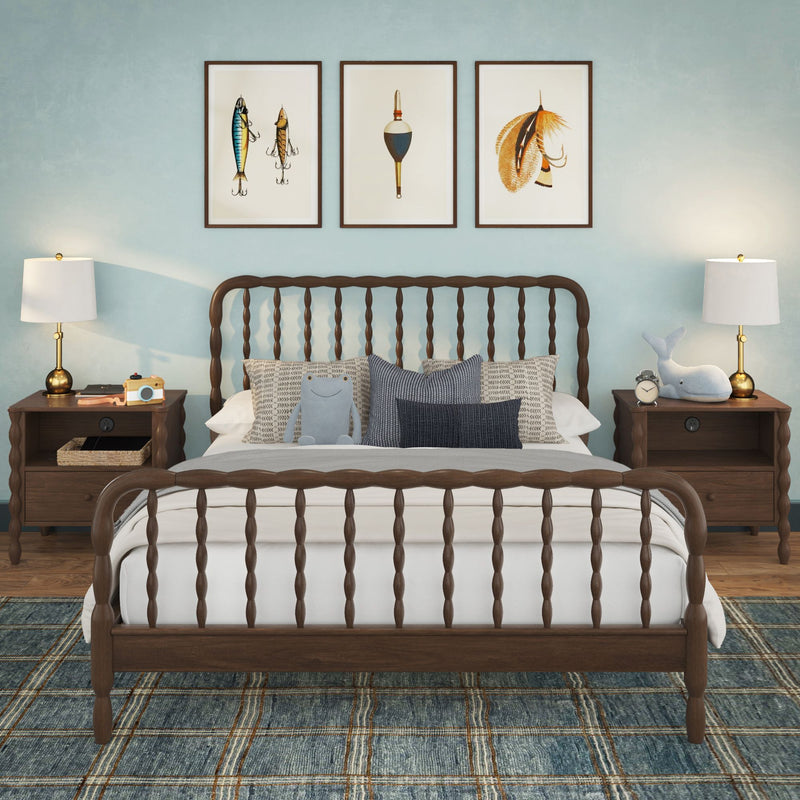 Coastal bedroom decor featuring a dark spindle wood bed against a light blue accent wall, three framed nautical fishing prints above the headboard, matching wood nightstands with brass lamps, textured pillows, a plush whale toy and a blue plaid rug