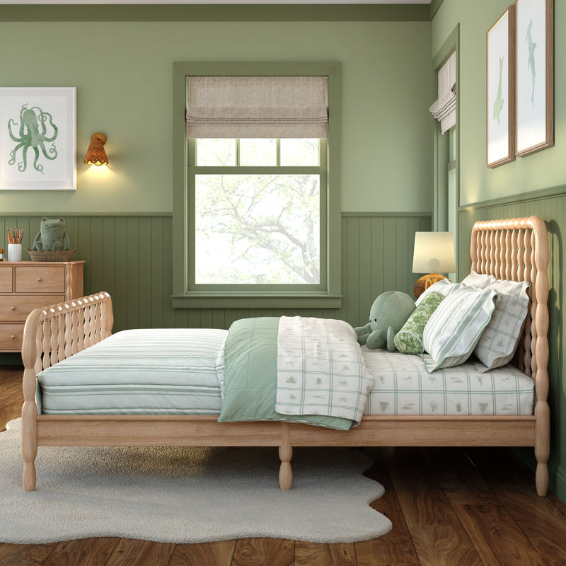 Green children's bedroom with wooden bed, mint bedding, octopus plush and framed sea creature art beside a window with a Roman shade