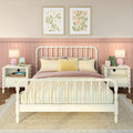 Pastel pink kids bedroom with white spindle bed, yellow gingham pillows, floral framed prints, scalloped wainscoting, bedside lamps and plush frog toy