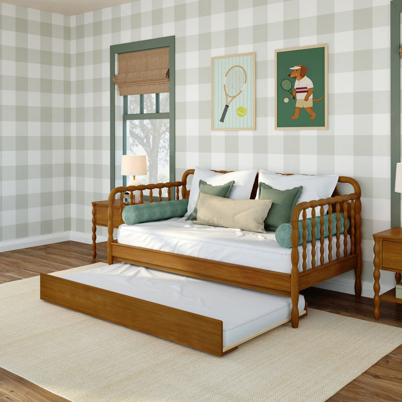 Cozy children's bedroom featuring a wooden daybed with pull-out trundle, green plaid wallpaper, roman shade, tennis-themed wall art and layered pillows
