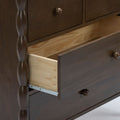 Dark brown wooden dresser with turned spindle detail and a partially open drawer revealing natural pine interior and metal drawer slide, bedroom storage furniture