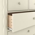 Cream painted wooden dresser close-up with a partially open drawer showing dovetail joints and a round knob
