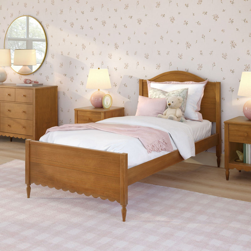 Cozy girl's bedroom with wooden twin bed, pink bedding and throw, floral wallpaper, teddy bear on pillow, round mirror and bedside lamps, nursery bedroom decor