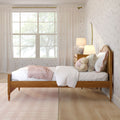 Cozy pastel girl's bedroom with wooden bed, pink throw blanket, plush teddy bear, bedside lamp, floral wallpaper and large window with sheer curtains