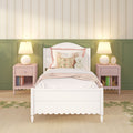 Pastel children's bedroom decor: white twin bed with floral pillows and teddy bear, green paneled wainscoting, pink nightstands with lamps and vintage floral striped wallpaper