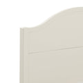 Close-up of cream white painted wood headboard with arched top and paneled farmhouse-style bedroom furniture detail