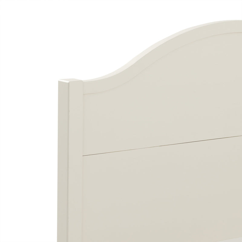 Close-up of cream white painted wood headboard with arched top and paneled farmhouse-style bedroom furniture detail