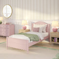 Pastel pink girl's bedroom with scalloped wooden bed, green throw, pink dresser, bedside lamps, round gold mirror and floral striped wallpaper