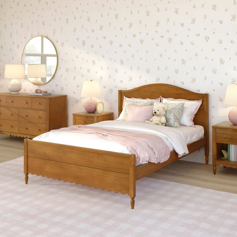 Cozy pink floral nursery bedroom with wooden bed and dresser, pastel bedding and pillows, plush teddy bear, round wall mirror and bedside lamps