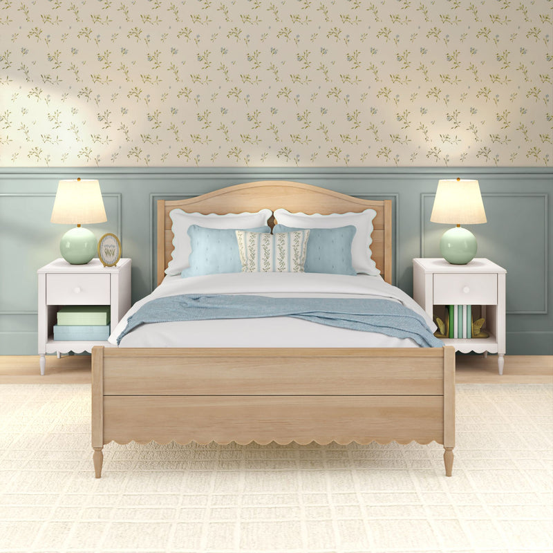 Cozy coastal cottage bedroom with light wood bed, blue and white pillows, floral wallpaper and mint ceramic bedside lamps on white nightstands