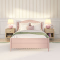 Pastel pink bedroom interior with scalloped headboard, floral striped wallpaper, matching pink bedside lamps, white pillows and green throw