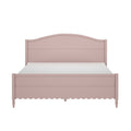 Blush pink wooden bed frame with arched headboard, scalloped footboard, turned legs and white mattress in cottage farmhouse style