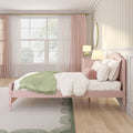 Pastel pink girls bedroom with pink bed, green throw blanket, sheer curtains, bedside lamp, round bolster pillow, and wall mirror