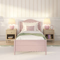 Pink scalloped twin bed with white bedding and green throw, matching nightstands and pink lamps in girls' bedroom with floral striped wallpaper