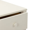 Close-up of cream-white wooden dresser drawer with round knob and slightly open drawer revealing natural wood interior