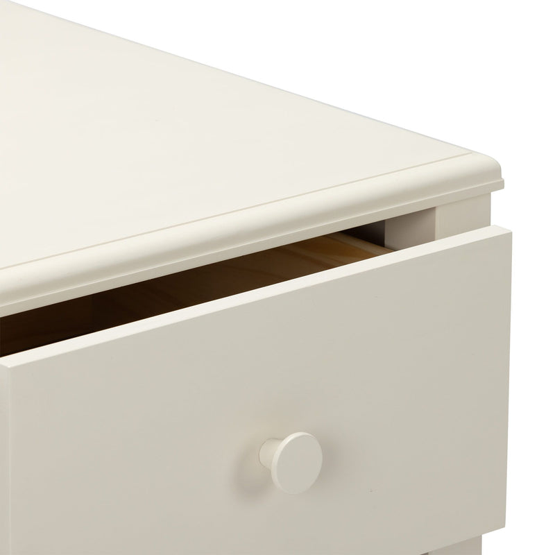 Close-up of cream-white wooden dresser drawer with round knob and slightly open drawer revealing natural wood interior