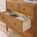 Mid-century light wood dresser with open drawer revealing neatly folded sweaters and knitwear — bedroom chest of drawers for storage and nursery decor