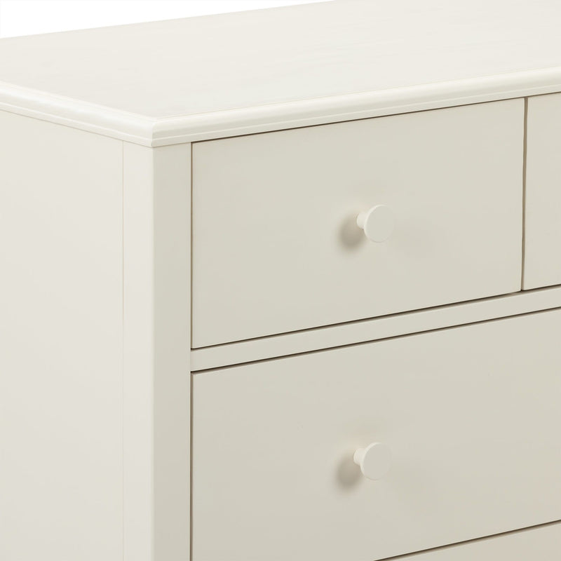 Close-up of cream painted wood dresser drawers with round knob and smooth beveled top — modern bedroom furniture