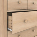 Light wood dresser (chest of drawers) with a partially open drawer revealing a metal slide and round wooden knobs