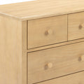 Close-up of light pine wood dresser with natural finish and round wooden knobs on a bedroom chest of drawers