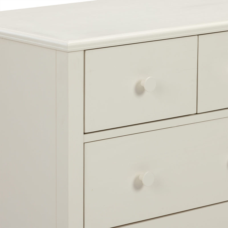 Close-up of white painted wooden dresser drawers with round knob and smooth beveled top edge, modern bedroom storage furniture