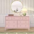Pastel pink six-drawer dresser with scalloped base, round gold mirror, green ceramic lamp and books against floral wallpaper — shabby-chic nursery decor