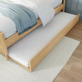 Wooden trundle bed with pull-out mattress, light oak frame, white bedding and blue throw — space-saving guest bed for small bedrooms