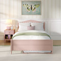Pastel pink bedroom with scalloped twin bed, white bedding and green throw, framed butterfly wall art, pink nightstand and lamp