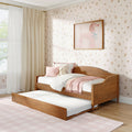 Children's bedroom with wooden twin trundle bed, pink bedding and pillows, plush teddy bear, floral wallpaper, framed poodle art and cream curtains