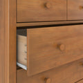 Close-up of solid wood dresser drawers with dovetail joinery and round wooden knobs, natural warm wood grain finish and a partially open drawer — bedroom furniture storage detail