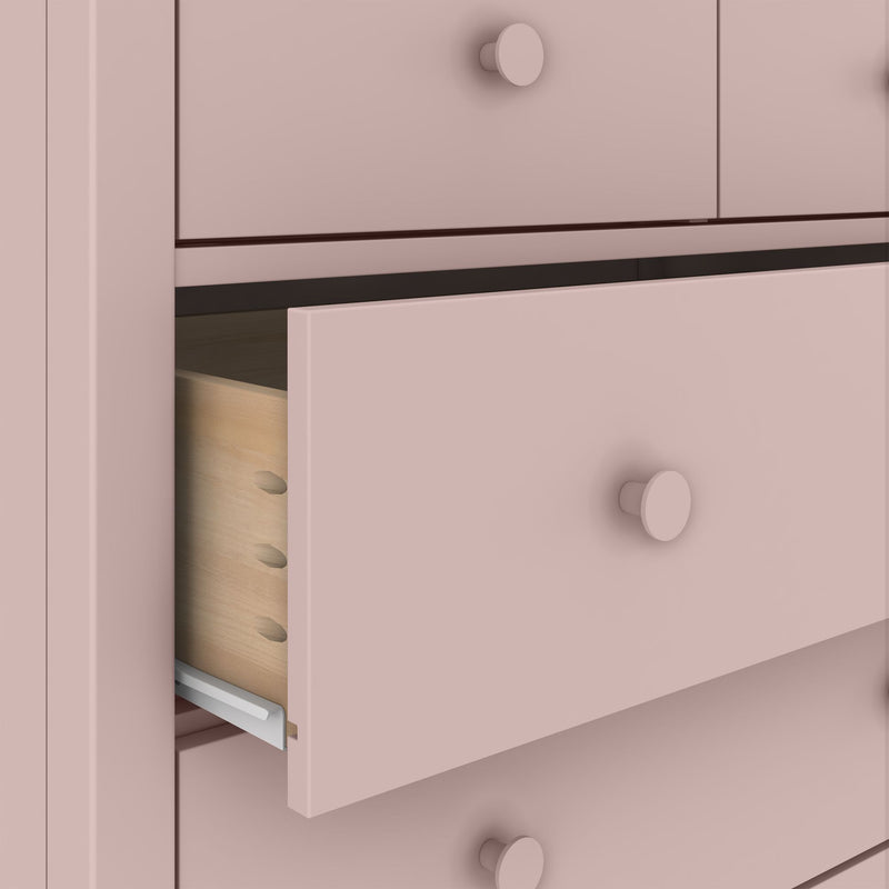 Soft pink wooden dresser drawer close-up with round knob, visible dovetail joinery and metal drawer slide
