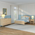 Coastal bedroom interior with blue striped wallpaper, light wood bed and dresser, pale blue wainscoting, sheer curtains over French doors, bedside lamps, swan artwork, braided rug and hardwood floor