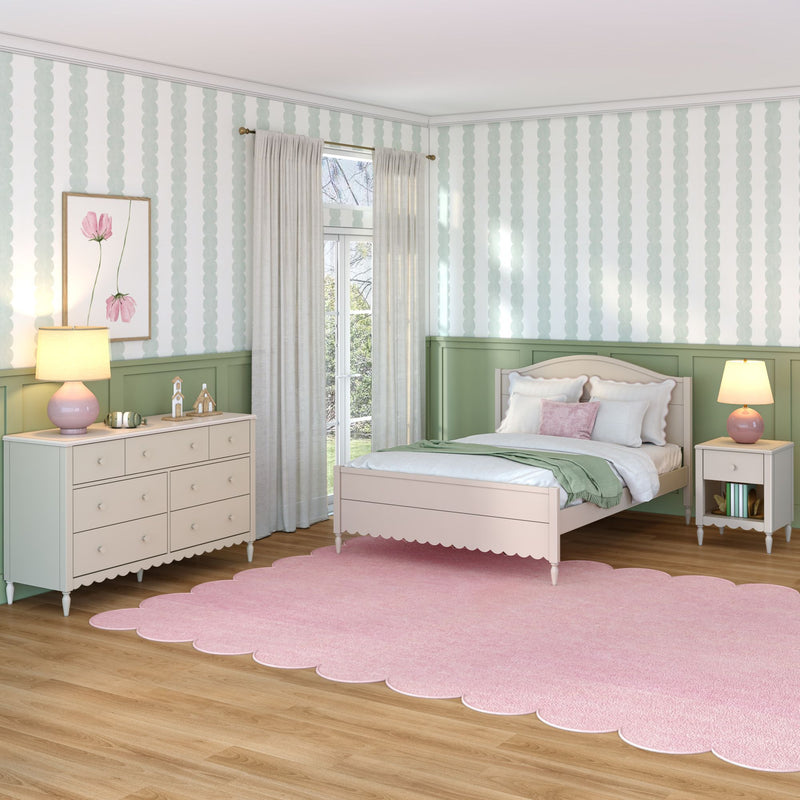 Pastel pink and sage green girls bedroom with scalloped pink rug, white twin bed, green wainscoting, floral wall art, sheer curtains and lamps, kids room decor