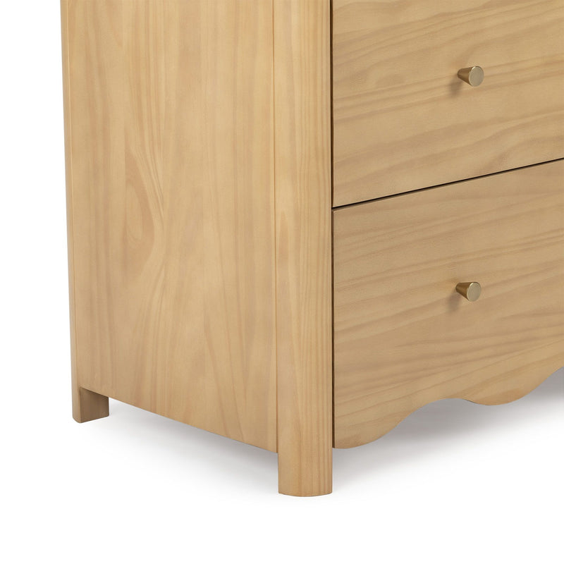 Close-up of a light natural wood nightstand with drawers, brass knob, rounded leg and scalloped apron, Scandinavian-style furniture
