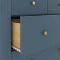 Matte blue dresser with partially open drawer showing light wood interior and round gold knobs
