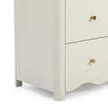 Close-up of cream wooden nightstand with scalloped apron, rounded legs and brass cone knobs for modern bedroom storage