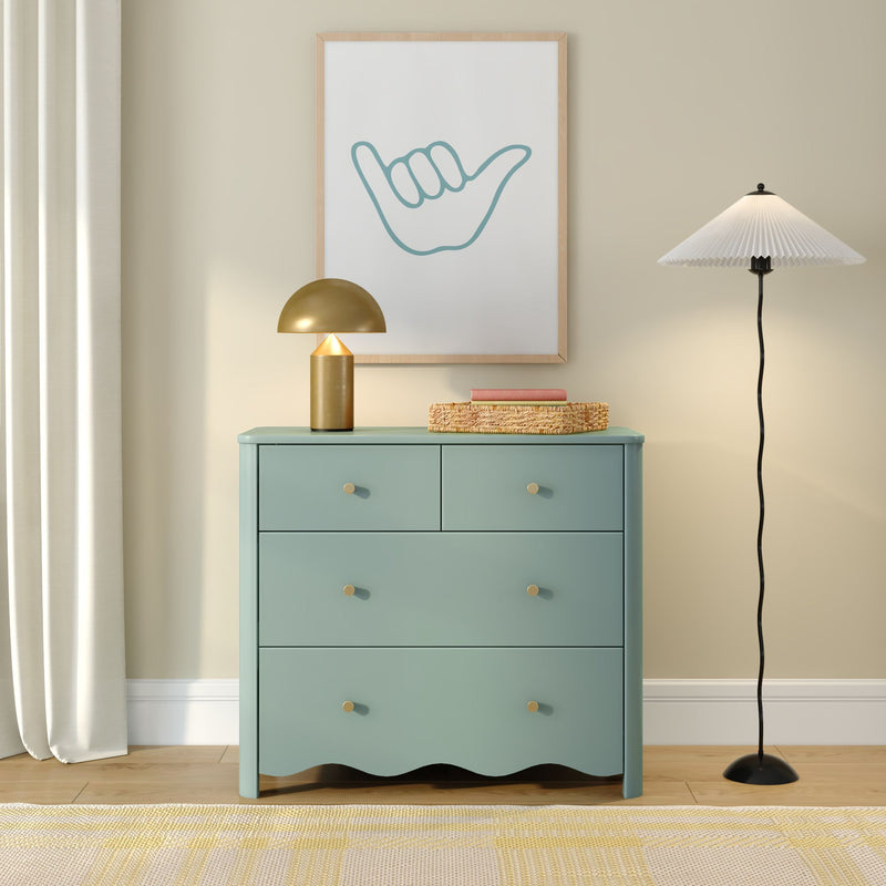 Modern coastal bedroom decor: mint teal dresser with gold table lamp, woven basket and framed minimalist shaka hand wall art
