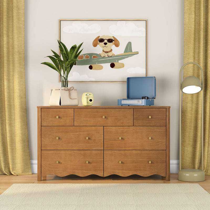 Kids room decor: wooden dresser with potted plant, yellow instant camera and blue record player, framed nursery wall art of a dog in sunglasses flying an airplane, yellow curtains.