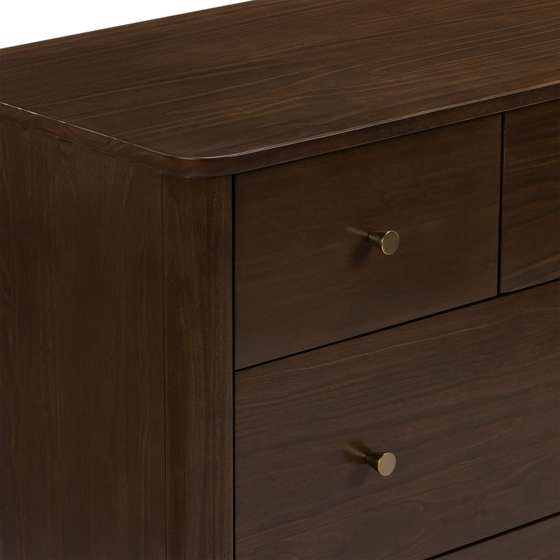 Close-up of a dark brown wooden dresser corner highlighting smooth wood grain finish and a round brass drawer knob