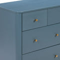Close-up of blue painted wooden dresser with matte finish and round brass drawer knobs, modern bedroom storage furniture