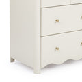 Close-up of cream three-drawer wooden nightstand with matte finish, gold brass cone knobs and scalloped apron, modern bedroom storage furniture