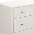 Close-up of a white modern dresser corner with rounded top edge and brass knob, minimalist bedroom nightstand drawers in matte cream finish